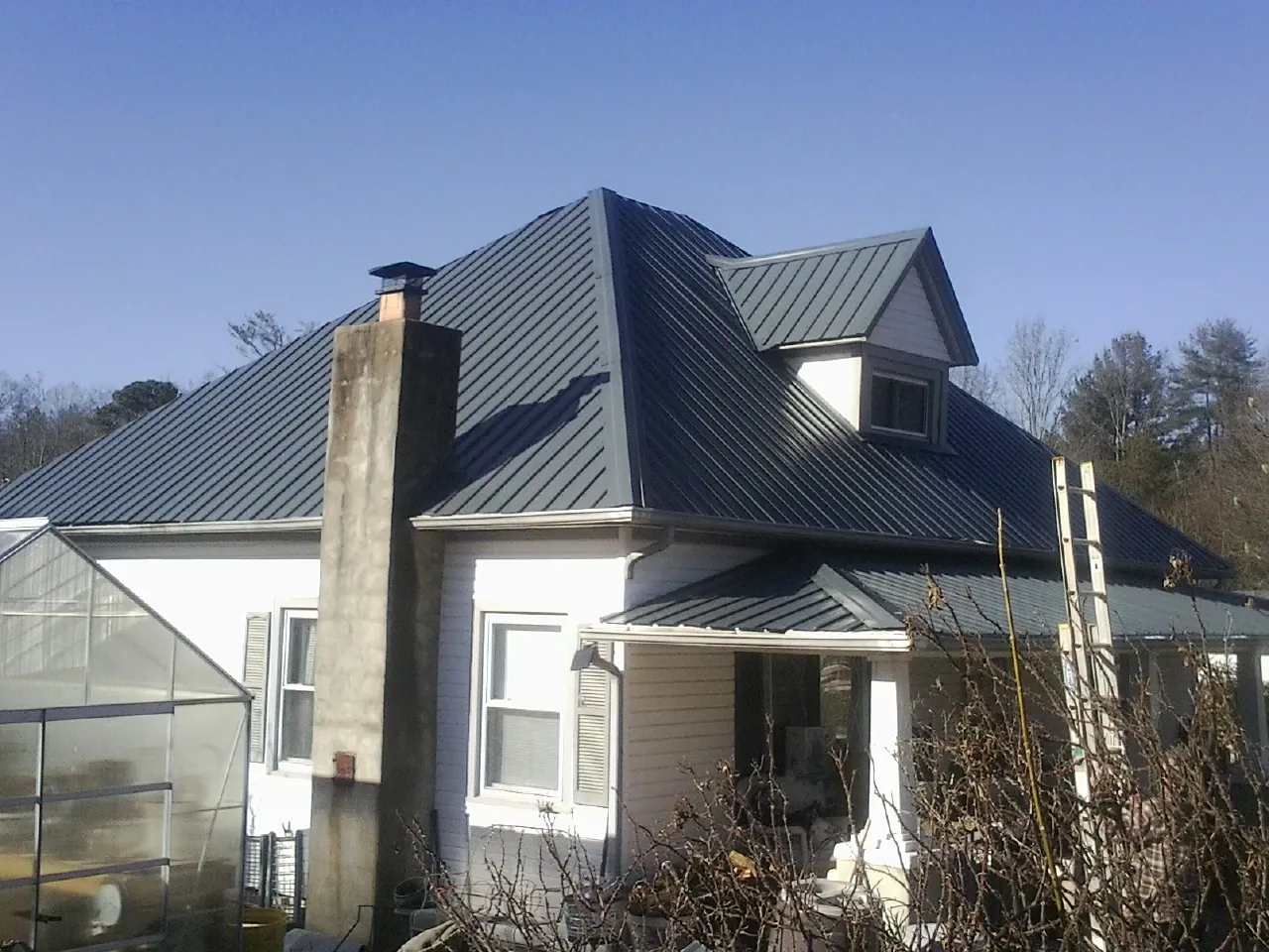 Dark blue standing seam metal roof on a white farmhouse with dormer — Slate & Tile Roof Repair by Roofing Brothers in Tilghman
