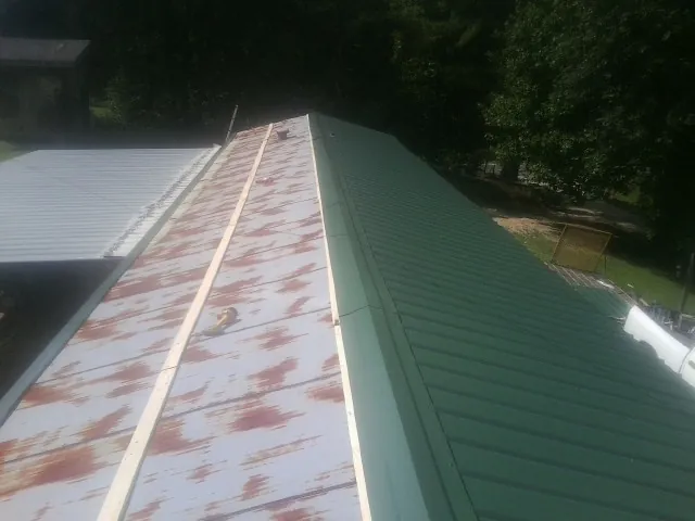 Old rusted panels beside newly installed green metal roofing — Wind Damage Roof Repair by Roofing Brothers in Tilghman