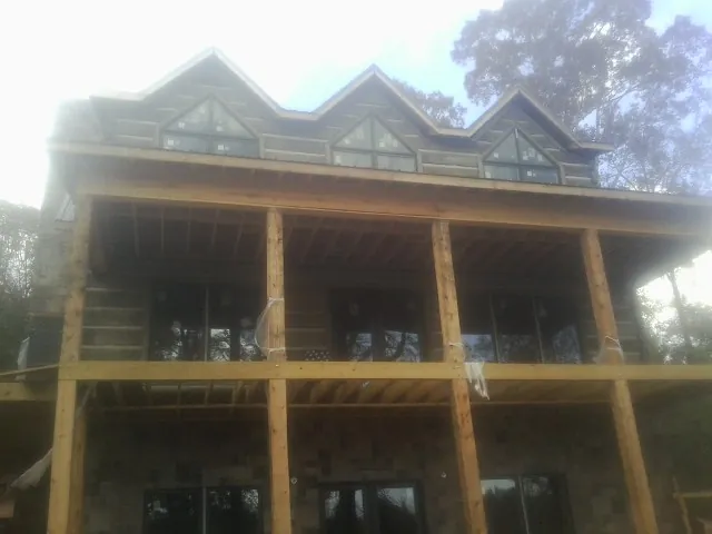 Dormers and porch framing on a large log home under construction — Roof Coating work by our crew in Tilghman