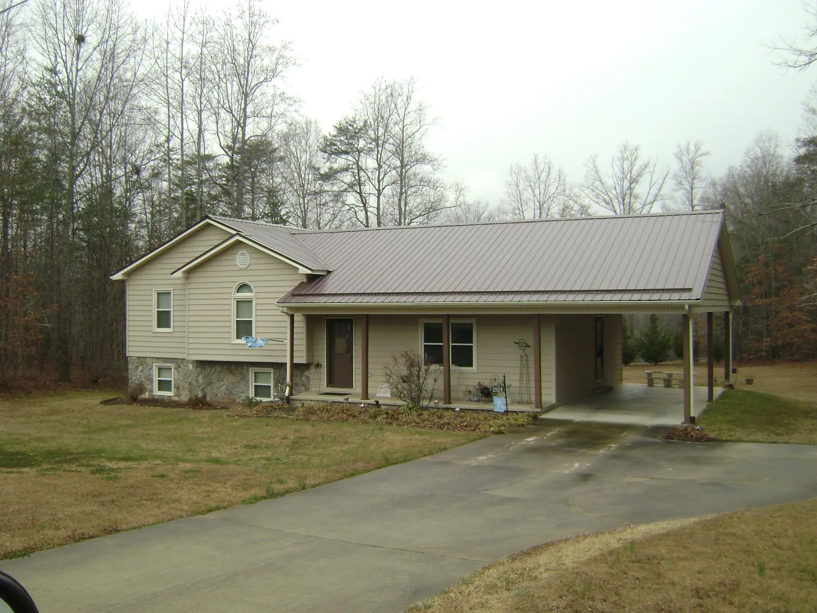 Brown metal roof on a tan split level home with an attached carport in Tilghman