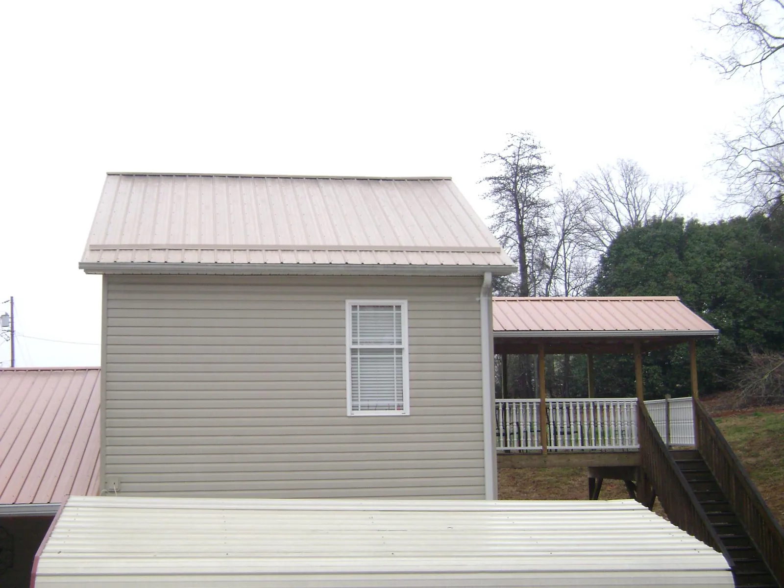 Tan metal roofs on a two story addition and attached porch, from a Roof Replacement job in Tilghman