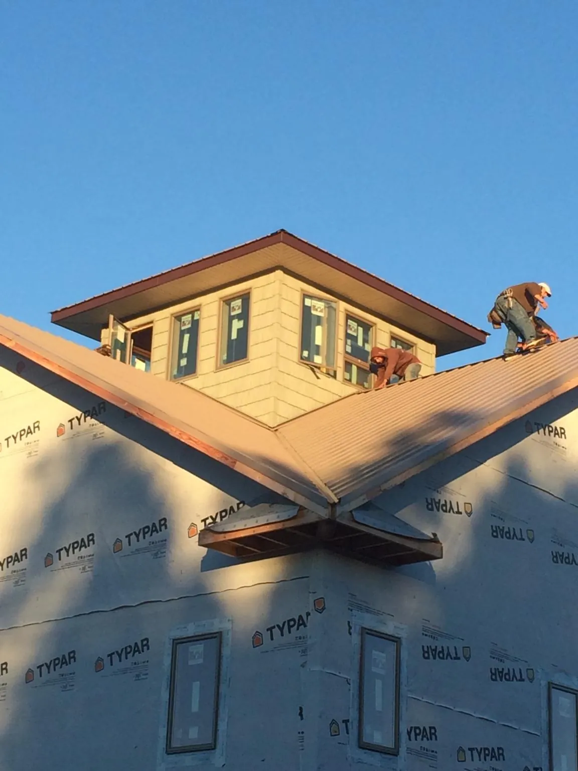 Roofers working around a rooftop cupola on a new metal roof at sunset — Roof Waterproofing in Tilghman by Roofing Brothers